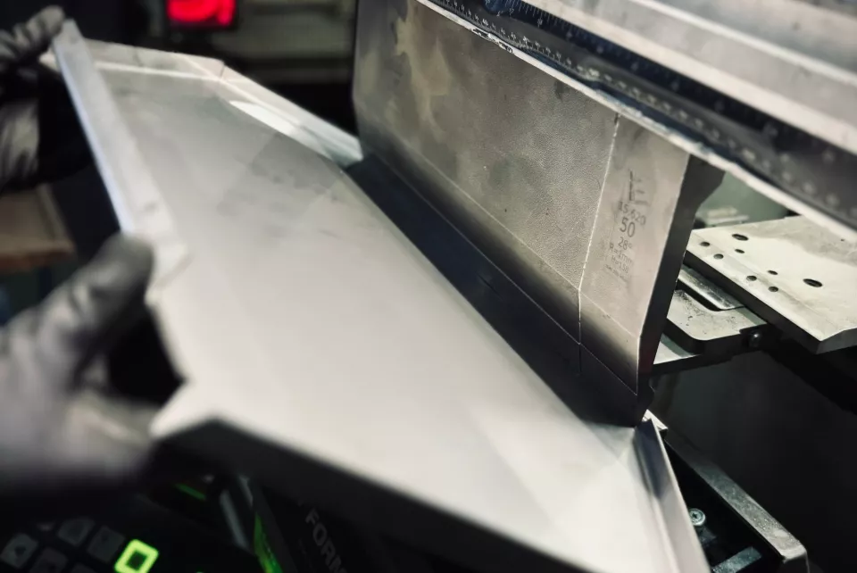 Metal sheet being bent by an industrial press.