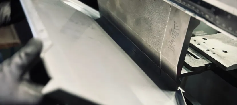 Metal sheet being bent by an industrial press.