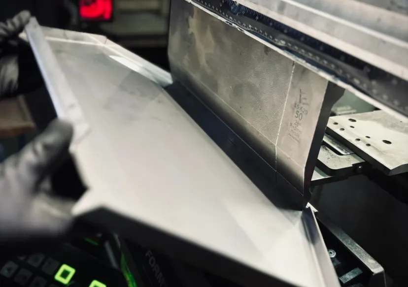 Metal sheet being bent by an industrial press.